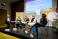 Podium sitzt im Halbkreis auf einer Bühne