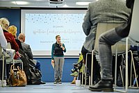 Britte Loschke steht mit einem Mikrofon in der Hand vor dem Publikum der Landesgesundheitskonferenz.