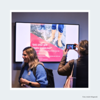 Teilnehmende der Veranstaltung stehen vor einem Bildschirm.